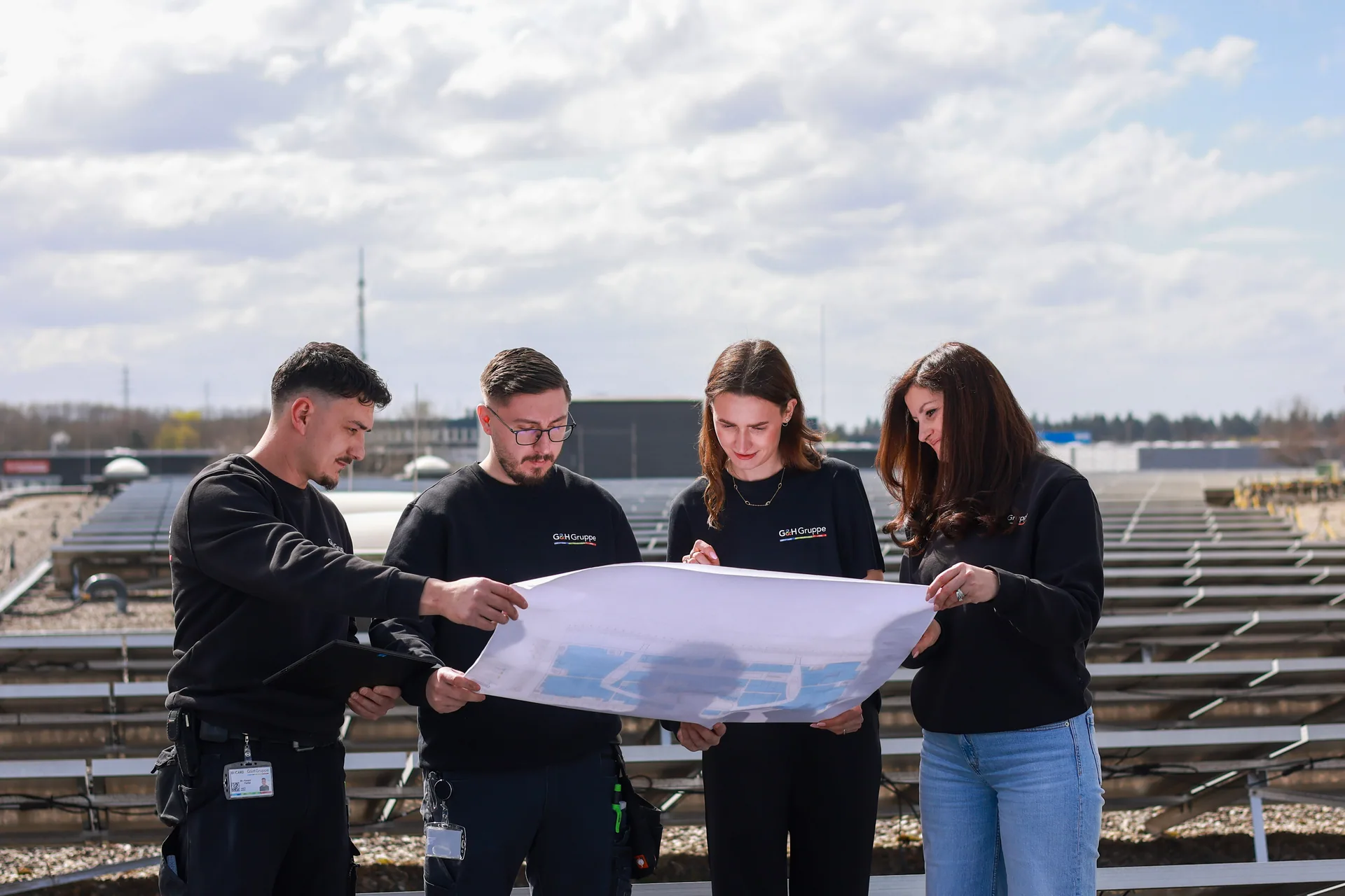 G&H Gruppe Team mit Projektplan auf dem Dach